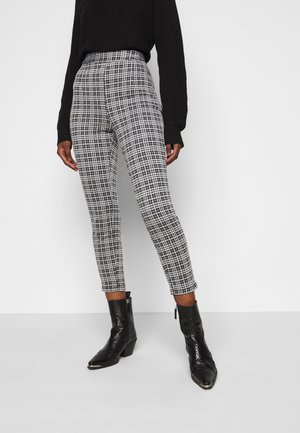 Pantalons taille haute à carreaux noir et blanc en tissu tissé, associés à des bottines noires à finition texturée.