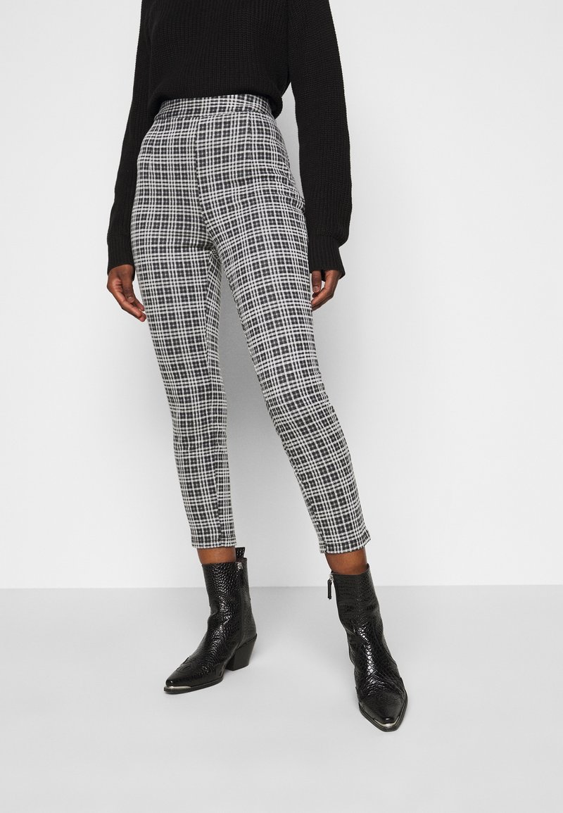 Svart och vit rutiga högmidjade byxor i vävd tyg, kombinerade med svarta anklar stövlar med strukturfinish.