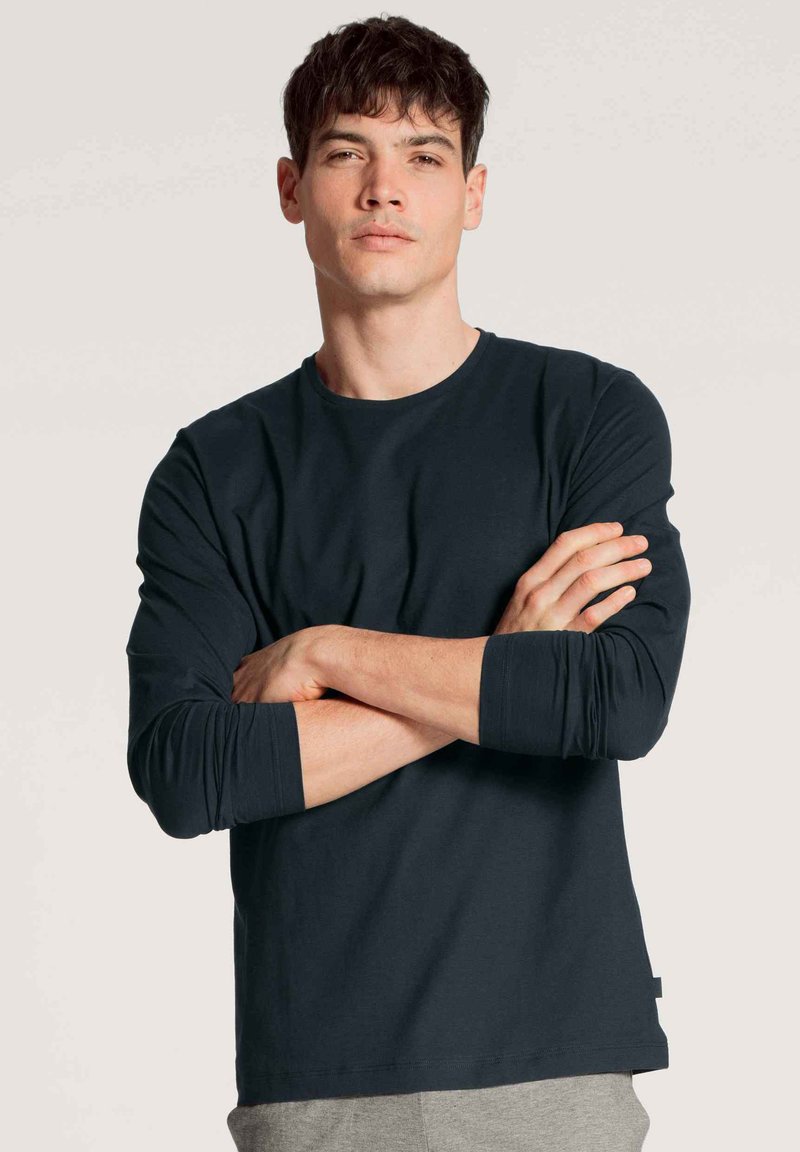 Donkerblauwe lange mouw shirt van zachte stof, met een ronde halslijn en opgerolde mouwen, met een rechte zoom en geen zichtbare patronen.