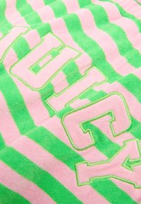Green and pink striped towel featuring plush texture, with large embroidered text in contrasting colors. Lines alternate between colors.