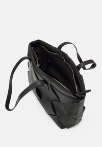 Svart läder tote-väska med vävt mönster, utrustad med dubbla handtag och blixtlåsfack, som visar en slät yta och rymligt inre.