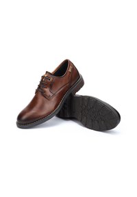 Zapatos de vestir de piel marrón con puntera redonda, cierre con cordones, suela de goma texturizada y detalles de costura a lo largo del borde.