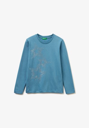 Camiseta de manga larga azul claro hecha de algodón, con un patrón de estrellas adornado con strass en el lado izquierdo. Cuello redondo.