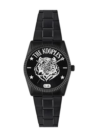 Sort metalur ur med et rundt ur, der præsenterer et design af en hvid tiger, fed skrift med teksten "The Kooples" og "L.A." samt stjernesymboler.