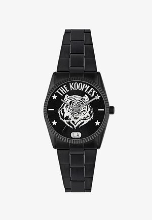 Črna kovinska ura s okroglo številčnico, ki prikazuje dizajn bele tigra, pogumno besedilo z napisom "The Kooples" in "L.A.", ter zvezdnate akcenti.