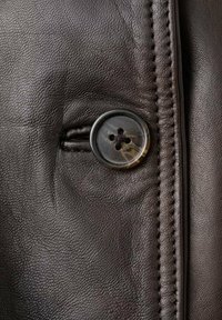 Piele maro închis cu un finisaj texturat, cu un nasture rotund cu patru găuri și cusături de-a lungul marginii.