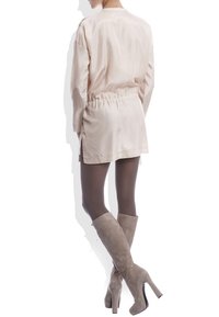 Light pink long-sleeve dress with cinched waist and split hem, paired with taupe over-the-knee suede boots and opaque tights.