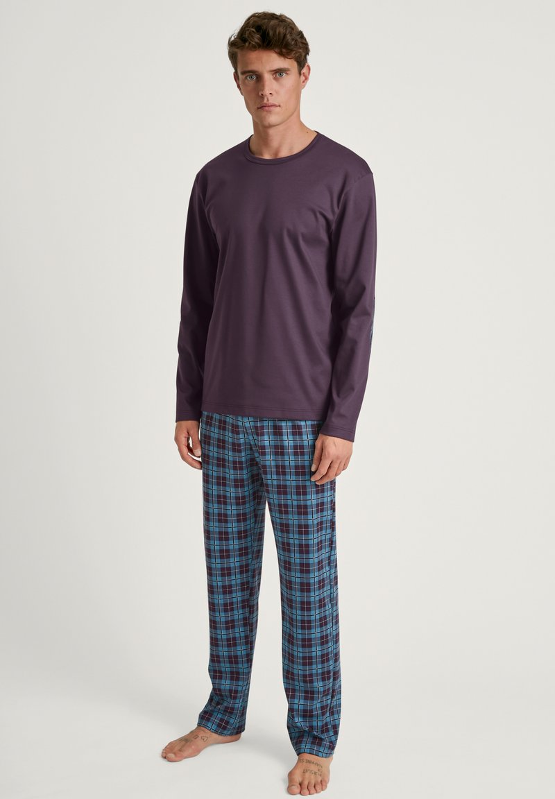Top violet à manches longues associé à un pantalon de pyjama à carreaux bleu, noir et blanc. Tissu doux, coupe décontractée et design léger.