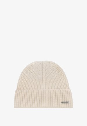 Beżowa, dzianinowa czapka z zawiniętym brzegiem i małą, prostokątną znaczkiem metalowym z logo na mankiecie.