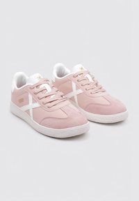 Sneakers in suede rosa con accenti bianchi, caratterizzati da una suola testurizzata e un design con lacci. Il tallone ha un leggero imbottito per maggiore comfort.