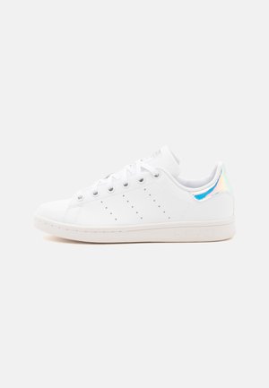 Sneaker bianca low-top con lacci bianchi, strisce laterali traforate e linguetta del tallone blu iridescente.
