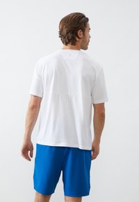 Λευκό κοντομάνικο μπλουζάκι με υφασμάτινη επάνω πάνελ, συνδυασμένο με μπλε σορτσάκι. Απλό σχέδιο, ελαφρύ υλικό και άνετη εφαρμογή.