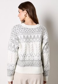 Gestrickter Pullover in Creme und Hellgrau. Verfügt über ein geometrisches Muster, eine Zopfmusterstruktur an den Ärmeln sowie einen gerippten Saum und Rundhalsausschnitt.