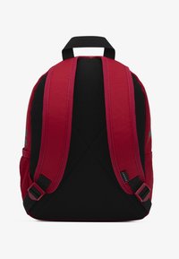 Κόκκινο ύφασμα σακίδιο με μαύρο πλέγμα στην πλάτη, μαξιλαρωμένους ιμάντες ώμου και πάνω λαβή. Διαθέτει λογότυπο και ρυθμιζόμενους πλαϊνούς ιμάντες.