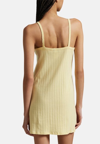 Yellow ribbed sleeveless dress with a fitted silhouette, scalloped trim, and a smooth texture, showcasing the back design.