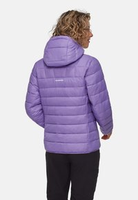 Veste isolante violette avec capuche, présentant un design matelassé et un logo au dos. Fabriquée en matériau léger et lisse.