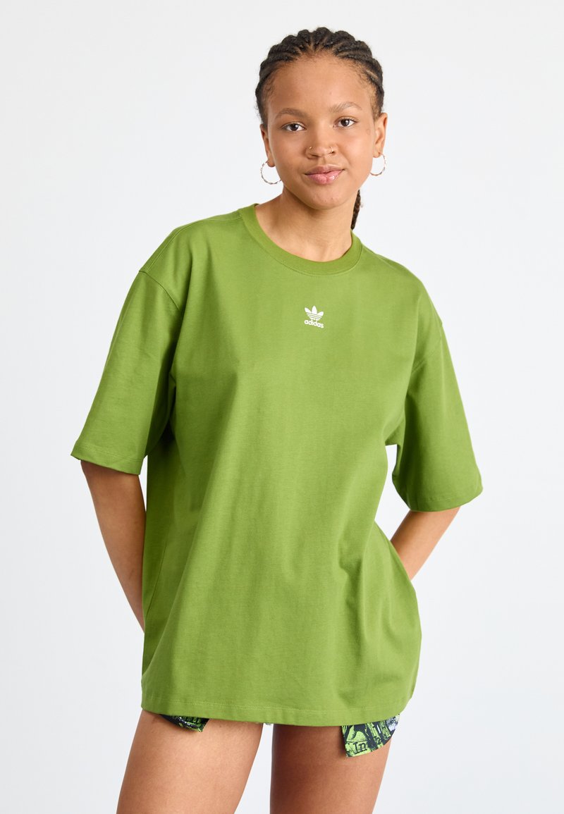 Grünes, übergroßes Baumwoll-T-Shirt mit rundem Ausschnitt und kurzen Ärmeln, das ein kleines weißes Adidas-Logo auf der Brust trägt.
