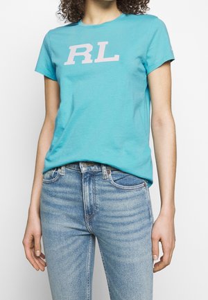 Turquoise cotton t-shirt featuring a light pink "RL" logo. Crew neck, short sleeves, and a relaxed fit. Paired with light blue jeans.