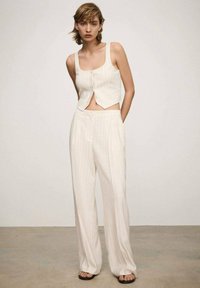 Top corto beige chiaro con bottoni frontali e pantaloni a gamba larga abbinati caratterizzati da righe verticali, realizzati in un tessuto testurizzato.
