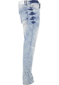 Vyprané modré rifle s priamym strihom, zdobené vzorom špliechanej farby a tradičným päťkapsovým dizajnom. Bavlnený materiál.