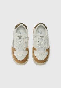 Sneakers med en ovandel i vit läder och beige mockaaccent, rund tå, perforerat mönster och dubbel kardborreband för en säker passform.