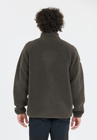 Mörkgrön fleece-tröja med hög krage, raglanärmar och texturerad tyg. Har elastiska ärmslut och en logotyp-patch på axeln.