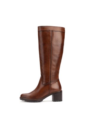 Bota marrón de piel hasta la rodilla con tacón de bloque y detalles cosidos, mostrada de perfil sobre fondo blanco.