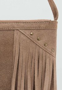 Borsa in suede marrone con dettagli in frange e borchie in ottone. La borsa ha una finitura testurizzata con una bordatura cucita nella parte superiore e una maniglia semplice.
