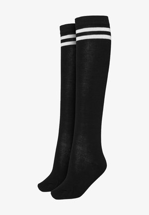 Juodos iki kelių kojinės su baltomis juostelėmis viršuje, pagamintos iš sklandžios, tamprios medžiagos, turinčios pritaikytą formą ir vienodą tekstūrą.