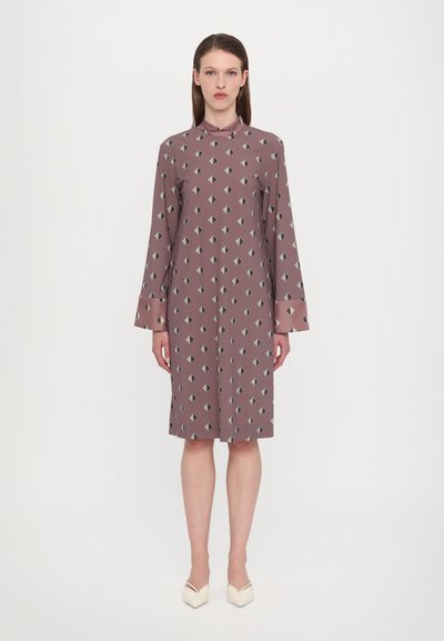 Long-sleeve, mauve dress with a geometric pattern featuring diamonds in dark green. High neckline and soft texture, reaching mid-calf.