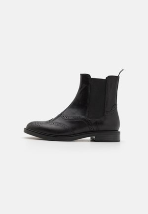 Botas de tornozelo em pele preta com painéis laterais elásticos, detalhes em brogue, ponta arredondada e um salto baixo em camadas.