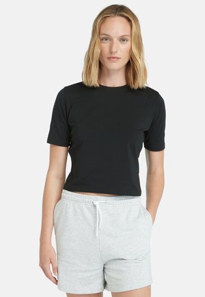 Black cropped t-shirt with short sleeves, made of smooth fabric. Paired with light gray, drawstring waist shorts.
