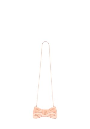 Rosaguld taske formet som en sløjfe i glat materiale med en tynd kædelås. Har en central knude og teksturede detaljer på sløjfen.