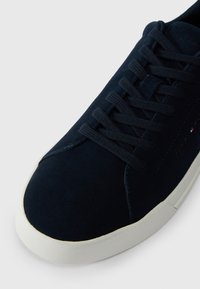 Zapatillas de ante marino con cordones a tono, suela de goma blanca, puntera redonda y un sutil logotipo en el lateral en un color contrastante.