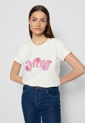 Witte katoenen t-shirt met opgerolde korte mouwen. Kenmerkt zich door een roze bloemenontwerp en de tekst "MOM" in vetgedrukte letters, gecombineerd met donkerblauwe jeans.