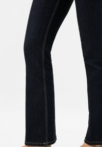 Dunkelblaue Denim-Jeans mit schmalem Schnitt, ausgestattet mit kontrastierendem goldgelbem Nähten entlang der Seitennähte und einem geraden Bein-Design.