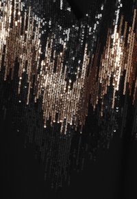 Zwarte kleding met een verloop van pailletten in goud, brons en zilver. De pailletten creëren een glanzende textuur met variërende maten.