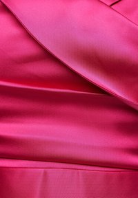 Satintyg i stark rosa med en slät textur; har överlappande sektioner som skapar ett lager-på-lager utseende.