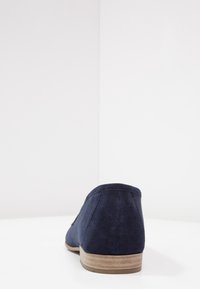 Granatowe zamszowe buty z niskim, zaokrąglonym obcasem i prostym, minimalistycznym designem. Tył ma gładką teksturę i subtelne detale w postaci przeszyć.