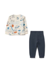 Haut crème à manches longues avec des imprimés colorés sur le thème de l'espace et une fermeture à bouton ; pantalon de survêtement en coton bleu marine avec taille élastique et poche latérale.