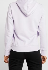 Hoodie lilla chiaro realizzato in morbido tessuto con cappuccio con cordino, polsini e orlo inferiore a coste, abbinato a pantaloni neri.