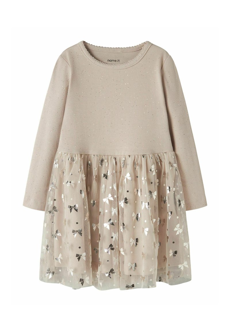 Robe à manches longues avec haut beige côtelé et jupe en tulle scintillante ornée de motifs de nœuds métalliques. Matière douce avec design en couches.