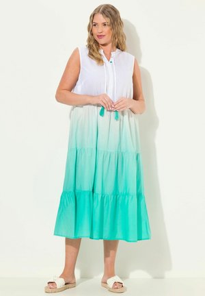 Robe sans manches avec un haut blanc et une jupe dégradée en aqua, présentant un design à volants, un tissu doux et des détails à pompons à la taille.