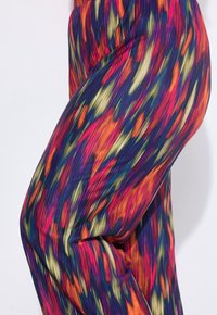 Leggings multicolor con un vibrante patrón abstracto de naranja, rosa, púrpura y verde. Fabricados con una tela suave y elástica con textura acanalada.