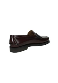 Mocassino in pelle marrone scuro con suola nera, tacco basso e cuciture in stile mocassino attorno all'area delle dita.