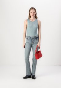 Tricou fără mâneci de culoare bleu deschis, blugi din denim deschis cu fustă evazată și o geantă mică roșie. Botine negre cu cusături decorative la tiv.
