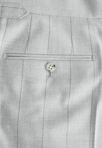 Helles grau tailliertes Jackenmaterial mit Nadelstreifen, ausgestattet mit einer aufgesetzten Tasche und einem Vierlochknopf in der Mitte. Glatte Textur.