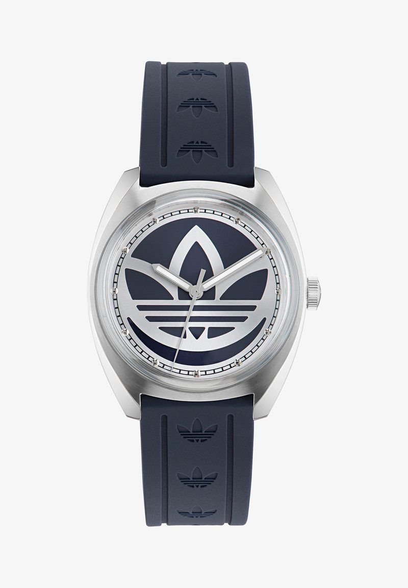 Jūras spēku gumijas siksniņš pulkstenis ar spīdīgu sudraba korpusu. Liels apaļš ciparnīca ar tonālu logotipa dizainu un sudraba stundu rādītājiem.