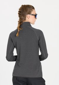 Graues Longsleeve-Sportoberteil mit hohem Kragen, aus strukturiertem Stoff und mit Kontrastnähten entlang der Nähte.