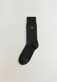 Svart bomullssocka med ribbat skaft och turkos logodetalj. Har en sömlös tådesign för komfort. Klassisk form och textur.
